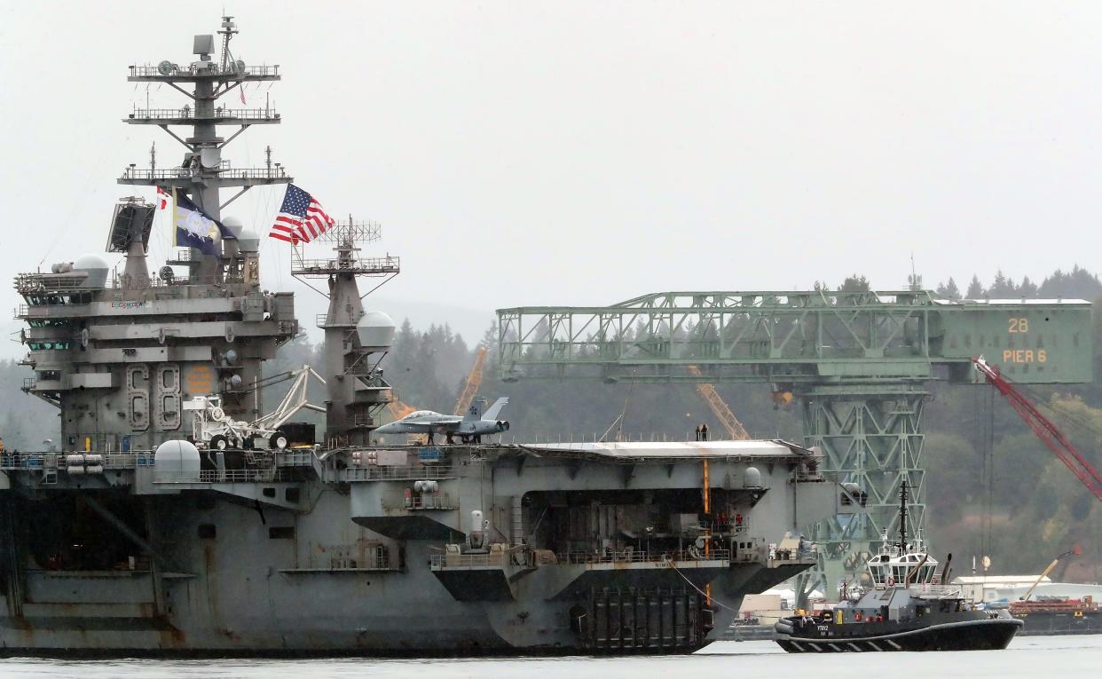 The USS Nimitz passes the Hammerhead Crane as it returns to Naval Base Kitsap on a rainy Sunday, Sept. 24, 2023.