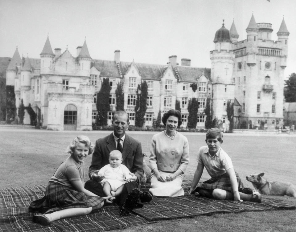 Baby Prince Andrew perches on Prince Philip's lap during a picnic on the grounds of Balmoral Castle. Also pictured are Queen Elizabeth, Prince Charles, and Princess Anne.