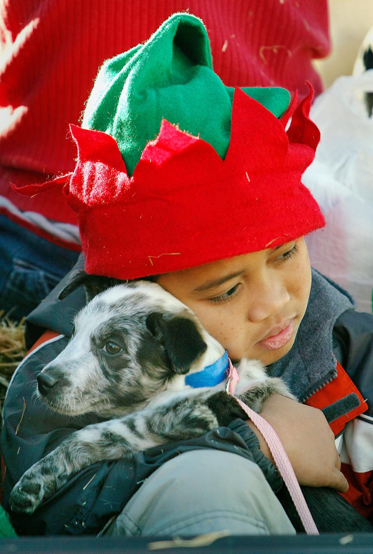 Marvin Prado of Iva hugs a puppy from the Anderson County Animal Shelter before the start of the city's Christmas parade in 2002. Workers from the shelter brought several dogs currently available for adoption to the parade.