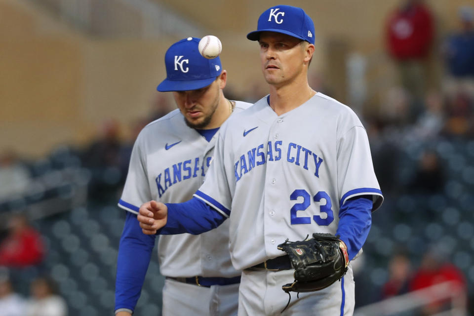 Kansas City Royals starting pitcher Zack Greinke juggles the ball after giving up back-to-back home runs to the Minnesota Twins, while he and Vinnie Pasquantino, left, await the manager to replace him during the fourth inning of a baseball game Thursday, April 27, 2023, in Minneapolis. (AP Photo/Bruce Kluckhohn)