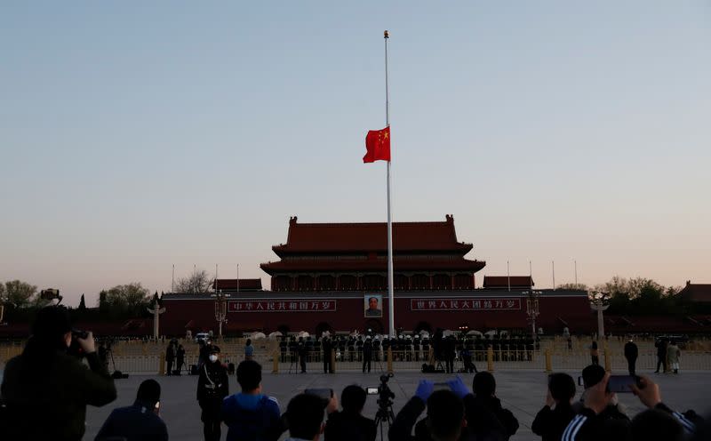 The Chinese national flag flies at half-mast during sunrise at Tiananmen Square in Beijing