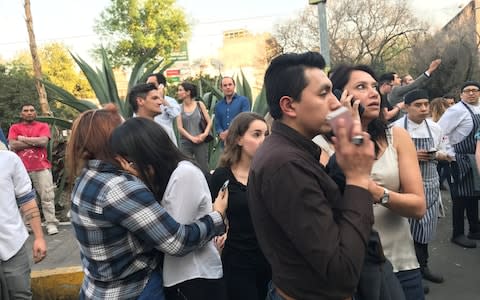 People stand on the street after an earthquake shook buildings in Mexico City