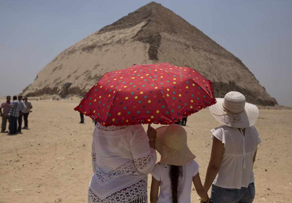 Women visit the Bent Pyramid during an during an event opening the pyramid and its satellites for visitors in Dashur, Egypt, Saturday, July 13, 2019. The Bent pyramid, listed on UNESCO's world heritage list as part of the Memphis necropolis, is considered a transition phase in pyramids construction that comes between step pyramids and complete pyramids. (AP Photo/Maya Alleruzzo)