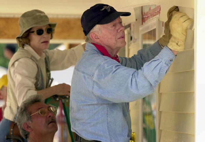 Jimmy Carter volt amerikai elnök és felesége, Rosalynn Carter a Habitat for Humanity otthona előtt állnak 2003-ban a georgiai LaGrange-ben.  Eric S. Lesser/Getty Images