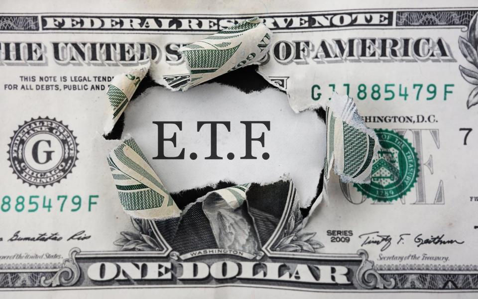 The letters "E.T.F." bursting through a dollar bill.