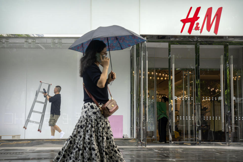 FILE - A worker carries a ladder as he works on a window display at an outlet of Sweden-based clothing company H&M at a shopping mall in Beijing, on May 16, 2023. Foreign companies are shifting investments and their Asian headquarters out of China as confidence plunges following the expansion of an anti-spying law and other challenges, the European Union Chamber of Commerce in China said Wednesday, June 21, 2023. (AP Photo/Mark Schiefelbein, File)