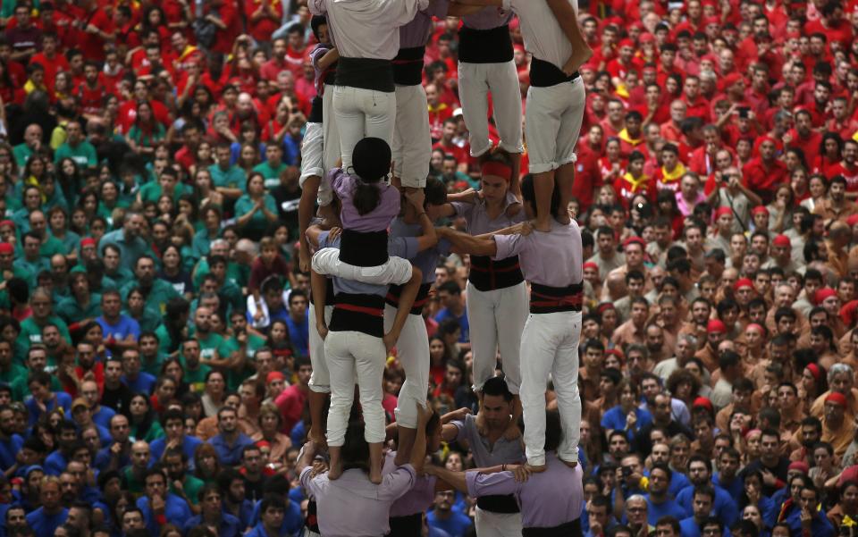 A girl climbs down as Castellers Colla Jove Xiquets de Tarragona form a human tower, called "castell", during a biannual competition in Tarragona city October 5, 2014. The formation of human towers is a tradition in the area of Catalonia. (REUTERS/Albert Gea)