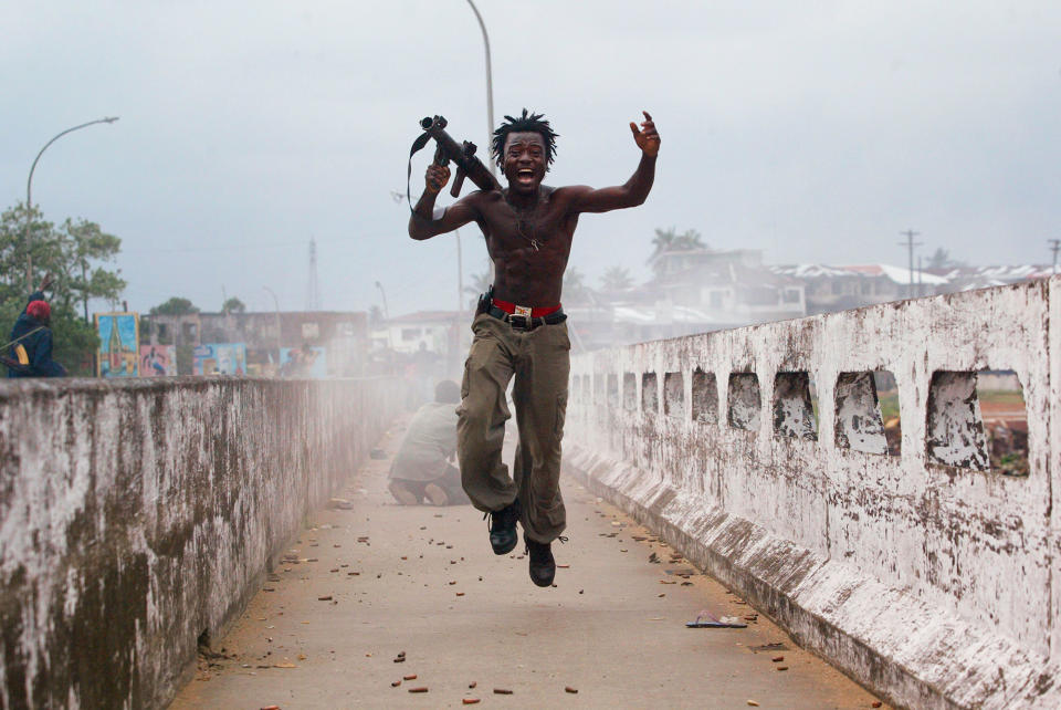 Joseph Duo, a Liberian militia commander loyal to the government, exults after firing a rocket-propelled grenade at rebel forces at a key strategic bridge July 20, 2003 in Monrovia, Liberia. (Photo: Chris Hondros/Getty Images)