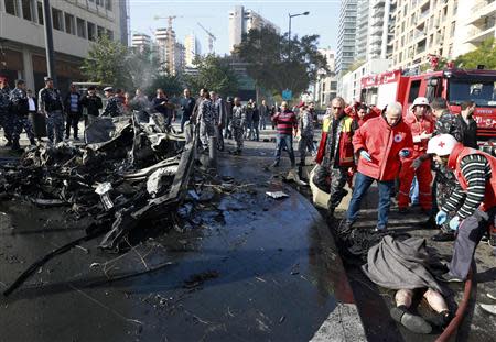 Lebanese Red Cross personnel cover a body near a destroyed car believed to be the vehicle in which former finance minister Mohammed Shattah was travelling in, after an explosion in Beirut's downtown area December 27, 2013. Shattah, who opposed Syrian President Bashar al-Assad, was killed in the explosion that targeted his convoy in Beirut on Friday along with at least four other people, security sources said. REUTERS/Jamal Saidi