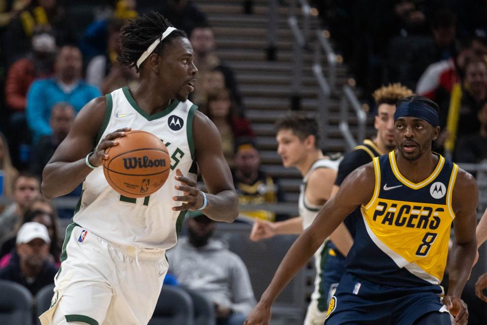 Nov 28, 2021; Indianapolis, Indiana, USA; Milwaukee Bucks guard Jrue Holiday (21) dribbles the ball while Indiana Pacers forward Justin Holiday (8) defends in the first half at Gainbridge Fieldhouse. Mandatory Credit: Trevor Ruszkowski-USA TODAY Sports