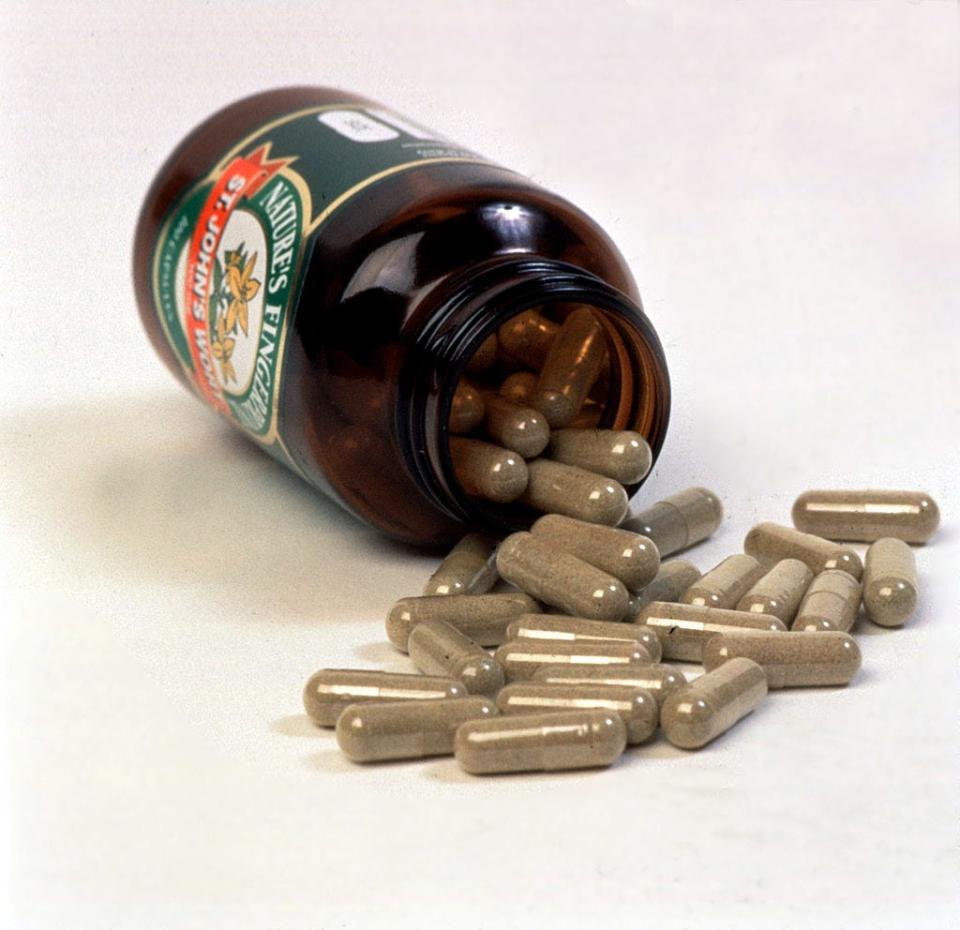 A brown bottle filled with St. John's Wort capsules. The bottle is turned over, and the capsules spill out.