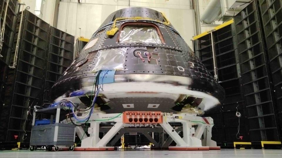 a shiny silver space capsule inside a big building with black and white walls.