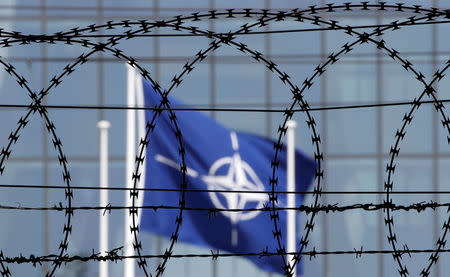 The NATO flag is seen through barbed wire as it flies in front of the new NATO Headquarters in Brussels, Belgium May 24, 2017. REUTERS/Christian Hartmann