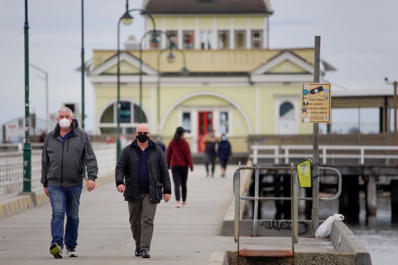 Walkers wear protective face masks at St Kilda pier in Melbourne, the first city in Australia to enforce mask-wearing to curb a resurgence of COVID-19