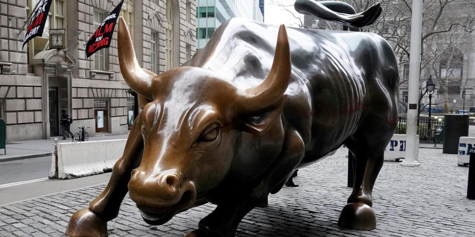 large bronze statue of bull in running stance in a brick plaza