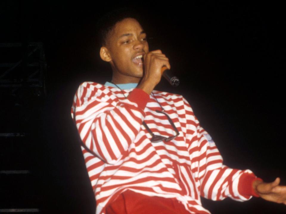 Will Smith wearing a red-and-white striped sweater and red pants while performing in 1988.