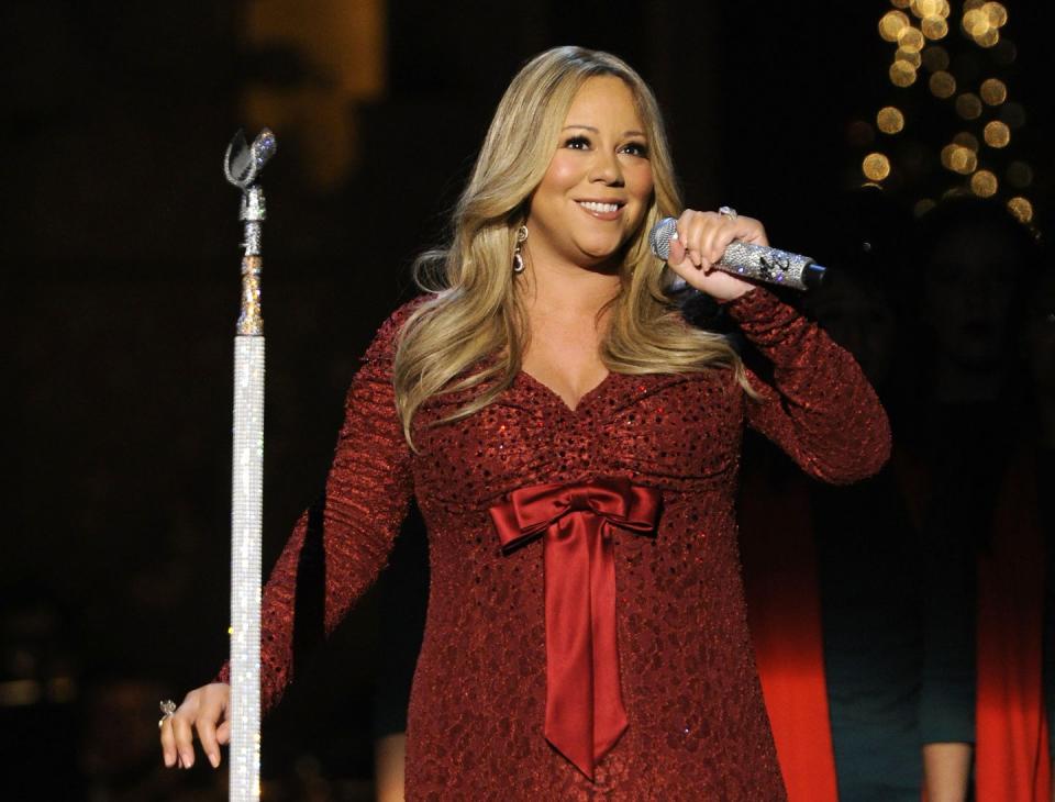 mariah carey wearing a red dress and smiling as she speaks into a microphone on a stage
