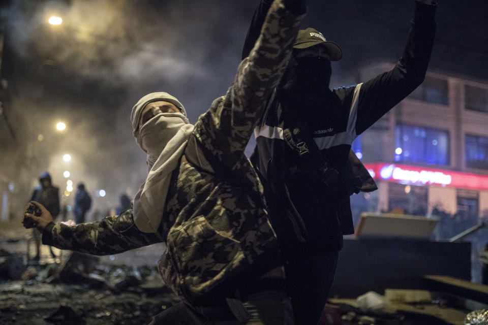 Un hombre con máscara y capucha arroja piedras a la policía el jueves 10 de septiembre de 2020 durante protestas por la muerte de un hombre a manos de la policía, en Bogotá, Colombia. (AP Foto/Iván Valencia)