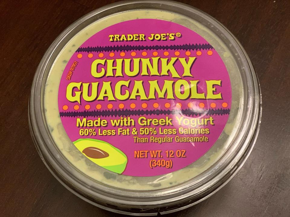 pink tub of trader joe's chunky guacamole with greek yogurt on wood table