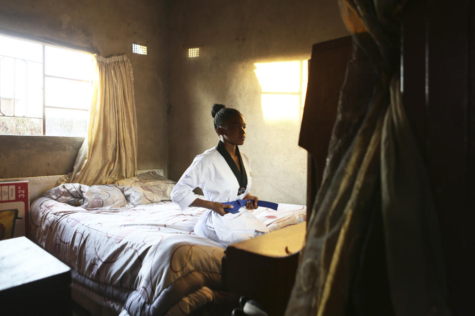 Natsiraishe Maritsa looks at the mirror inside her room in the Epworth settlement about 15 km southeast of the capital Harare, Saturday Nov. 7, 2020. In Zimbabwe, where girls as young as 10 are forced to marry due to poverty or traditional and religious practices, a teenage martial arts fan 17-year old Natsiraishe Maritsa is using the sport to give girls in an impoverished community a fighting chance at life. (AP Photo/Tsvangirayi Mukwazhi)