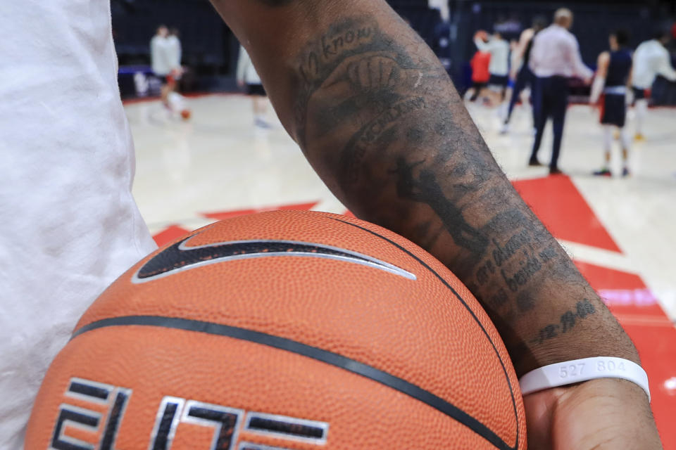 In this Feb. 22, 2020, photo, Dayton's Trey Landers stands on the court prior to the team's NCAA college basketball game against Duquesne in Dayton, Ohio. The tattoo on his arm says "Dad I know you are always walking beside me" in honor of his father, who was fatally shot when Landers was 8 years old. (AP Photo/Aaron Doster)