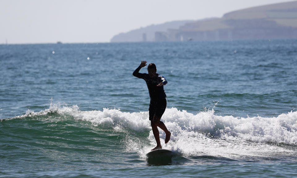 A surfer takes to the water at Bournemouth beach, as visitors have taken to the sand to make the most of the hot weekend weather across the UK.