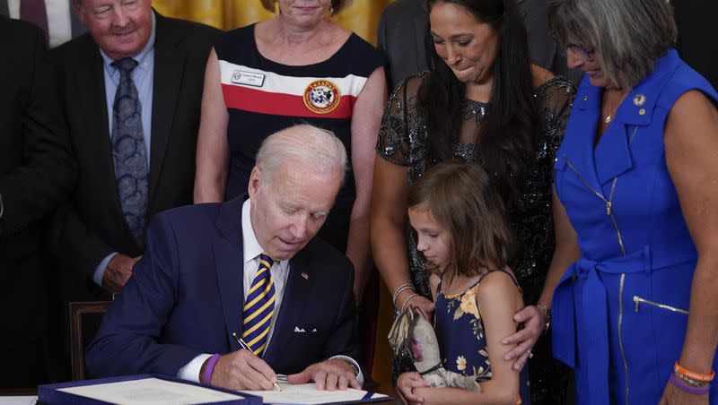 Danielle and Brielle Robinson, the wife and daughter of Sgt. 1st Class Heath Robinson, who died of cancer two years ago, watch as President Joe Biden signs the “PACT Act of 2022” during a ceremony in the East Room of the White House on Aug. 10, 2022, in Washington. Hundreds of thousands of veterans have received additional benefits in the past year after Biden signed legislation expanding coverage for conditions connected to burn pits that were used to destroy trash and potentially toxic materials.