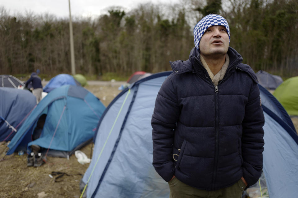 In this photo taken on Tuesday, Jan.15, 2019, Ahmed, from Ahwaz in southwest Iran, looks up next to tents in Calais, northern France, Land, sea and air patrols are combing the beaches, dunes and frigid, murky coastal waters of northern France, the gateway to Britain, in a bid to stop migrants, mostly Iranian, from an ever more risky tactic to sneak across the English Channel _ in small boats and rubber rafts. (AP Photo/Michel Spingler)