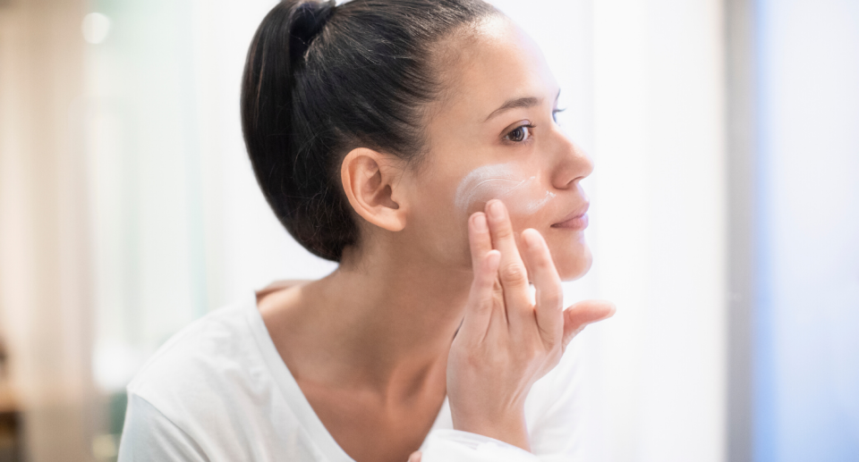 Woman applying cream on her face