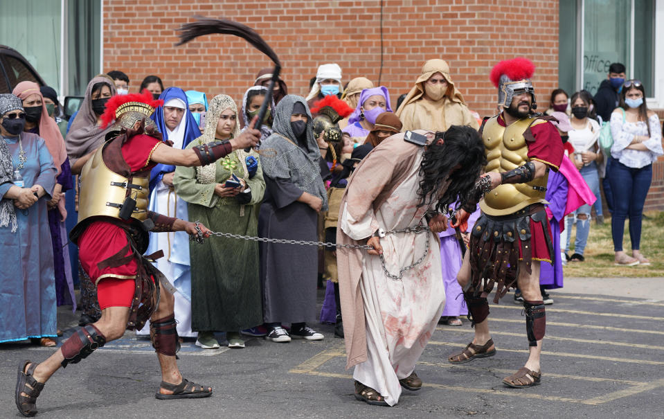 Actors portraying soldiers guide a man playing Jesus Christ during an outdoor reenactment of the Stations of the Cross at St. Anthony of Padua Catholic Church on Friday, April 2, 2021, in west Denver. Parishioners walked through the neighborhood as part of the service. (AP Photo/David Zalubowski)