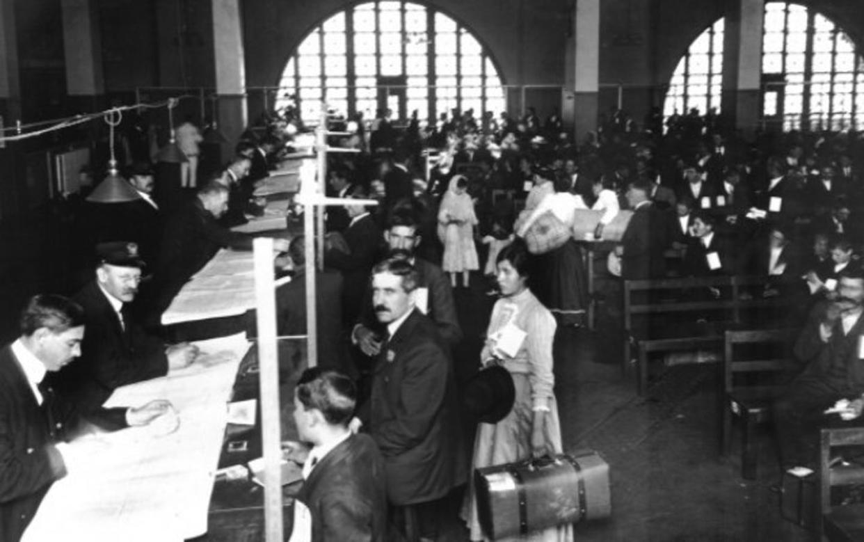Immigrants and inspectors in the registry room for legal inspections at Ellis Island.