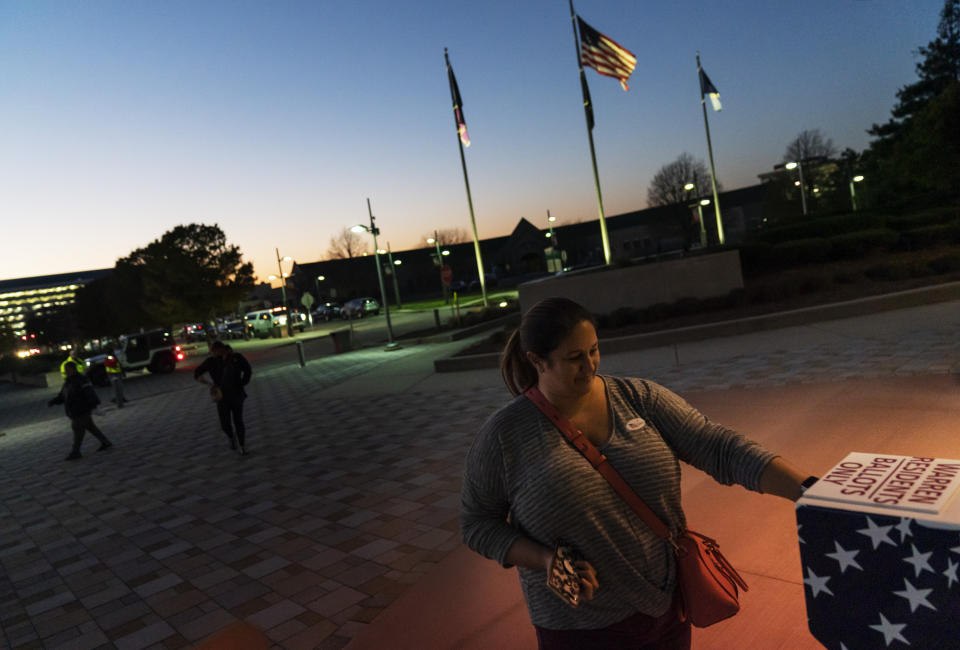 FILE - In this Tuesday, Nov. 3, 2020 file photo, Wendy Gill inserts her absentee ballot at a drop-off box as the sun sets on Election Day outside City Hall in Warren, Mich. The pandemic triggered wholesale changes to the way Americans voted in 2020, but that's no guarantee measures making it easier to cast ballots will stick around for future elections. (AP Photo/David Goldman)