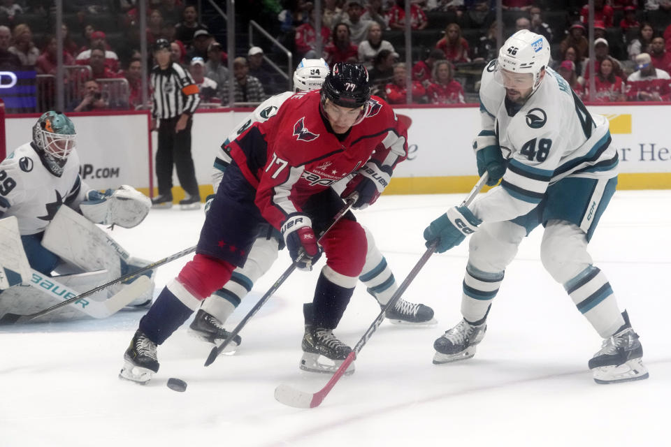 Washington Capitals right wing T.J. Oshie (77) tries to maneuver the puck past San Jose Sharks center Tomas Hertl (48) in the first period of an NHL hockey game, Sunday, Oct. 29, 2023, in Washington. (AP Photo/Mark Schiefelbein)