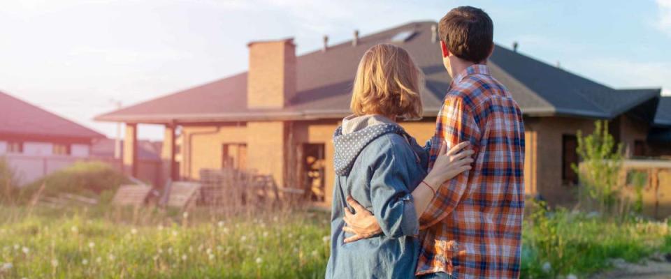 Back view of happy family is standing near their new modern house and hugging