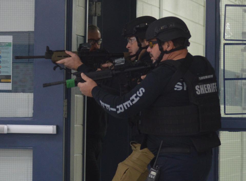 Law enforcement fires off marker rounds subduing a mock shooter who had moved into a cafeteria surrounded by students wearing tags explaining their injuries and conditions.