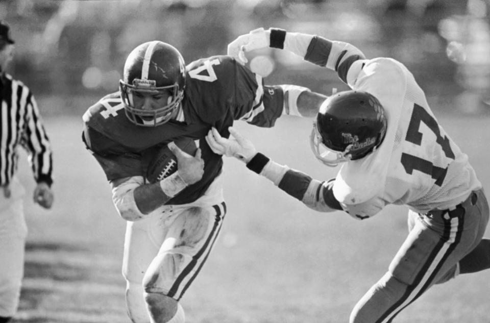 Holy Cross running back Gill Fenerty, left, breaks a tackle by Western Carolina University defensive back Miles Nicholson, right, on the way to a touchdown in the second period of the NCAA Division 1-AA quarterfinal playoff game at Fitton Field  on Dec. 5, 1983. Western Carolina defeated Holy Cross, 28-21.