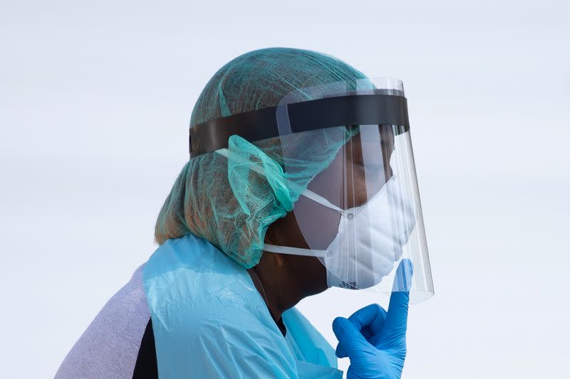 FILE PHOTO: Healthcare worker points towards her mask at COVID-19 drive in testing location in Houston, Texas