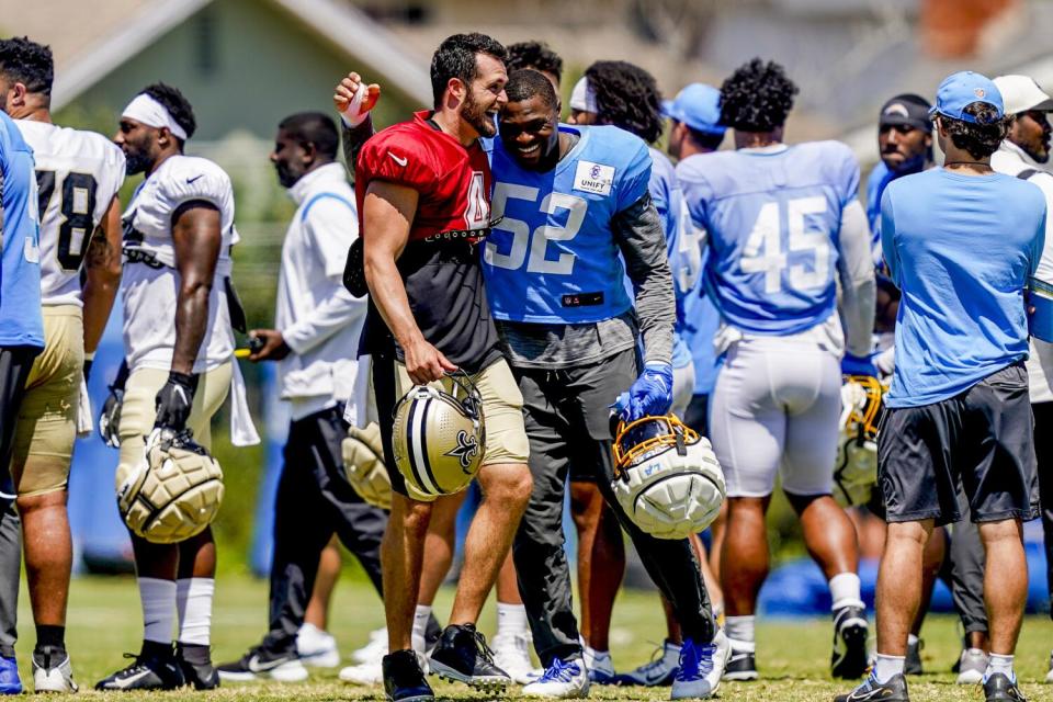 Chargers linebacker Khalil Mack (52) hugs Saints quarterback Derek Carr (4) after their joint practice.