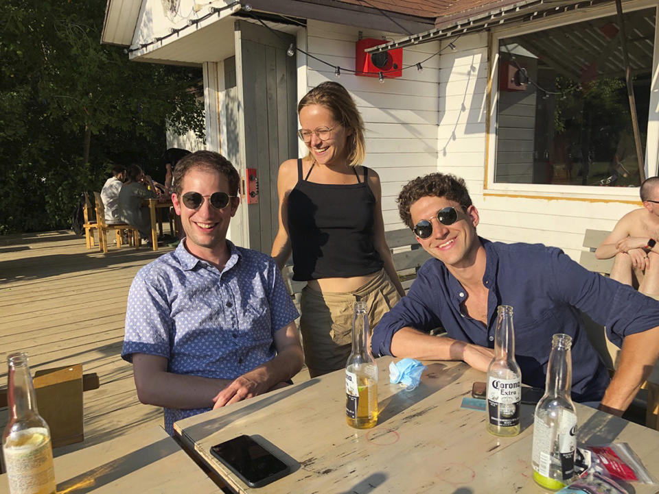 In this photo taken by Lilia Khazhieva, Wall Street Journal reporter Evan Gershkovich, left, Financial Times reporter Polina Ivanova, center, and Guardian reporter Pjotr Sauer pose at a dacha in the Moscow region. Gershkovich was arrested in March 2023 on espionage charges, which he, his employer and the U.S. government deny. (Lilia Khazhieva via AP)