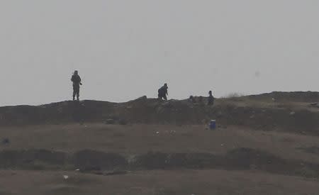 Armed men, presumed by local sources to be Islamic State fighters, are pictured at a checkpoint in the west of Syrian town of Kobani, seen from near the Mursitpinar border crossing on the Turkish-Syrian border in the southeastern town of Suruc in Sanliurfa province October 13, 2014. REUTERS/Umit Bektas