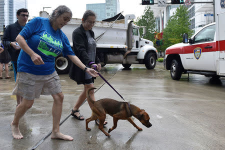 Evacuees Robin Alter (L) and her daughter Melissa Alter walk their dog Dexter into the George R. Brown Convention Center after Hurricane Harvey inundated the Texas Gulf coast with rain causing widespread flooding, in Houston, Texas, U.S. August 27, 2017. REUTERS/Nick Oxford