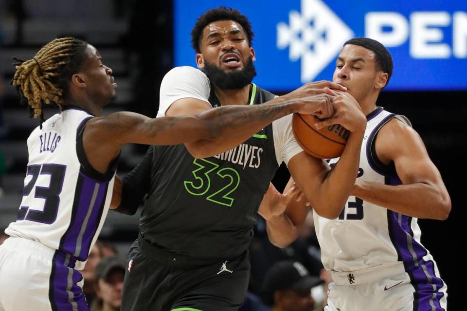 Minnesota Timberwolves forward Karl-Anthony Towns (32) looks to get away from the defensive pressure of Sacramento Kings guard Keon Ellis (23) and forward Keegan Murray (13) in the first quarter Friday at Target Center in Minneapolis.