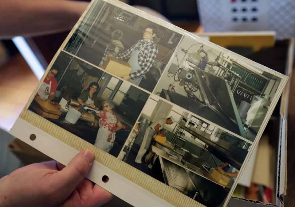 Jon Metzig holds a sleeve of photos from a family album May 23, 2023, at Union Star Cheese Factory. The photos show family and employees working at the factory.