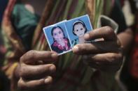 A woman holds a picture of her daughter (L), a garment worker who went missing in the Rana Plaza collapse, next to a picture of the worker's daughter on the first year anniversary of the accident, as people gather in Savar April 24, 2014. Protesters and family members of victims demand compensation on the one year anniversary of the collapse of Rana Plaza, in which more than 1,100 factory workers were killed and 2,500 others were injured.