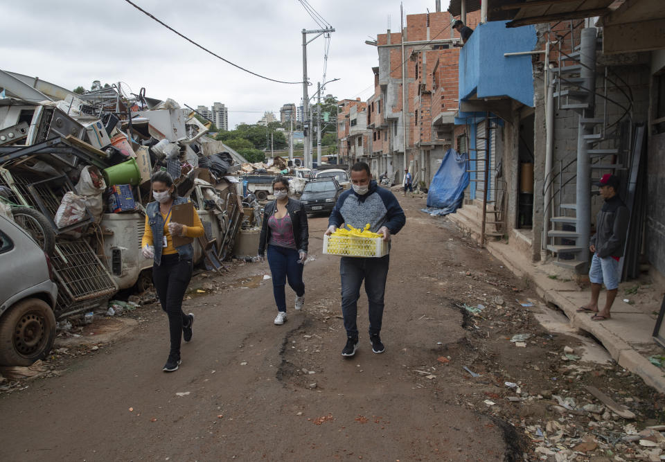 Volunteers carry meals to be distributed to residents in the Paraisopolis slum during a quarantine imposed by the state government to help stop the spread of the new coronavirus in Sao Paulo, Brazil, Wednesday, April 8, 2020. (AP Photo/Andre Penner)