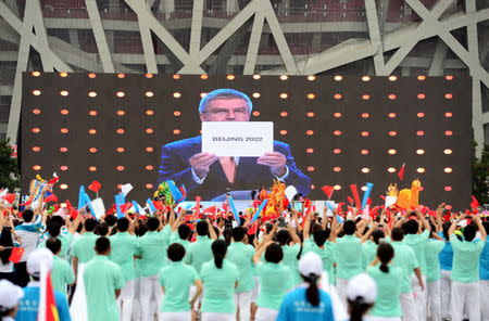 People cheer as they watch on a screen the IOC announcing Beijing as the winner city for the 2022 winter Olympics bid, outside the Birds' Nest, also known as the National Stadium, in Beijing, China, July 31, 2015. REUTERS/Stringer