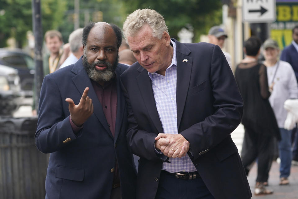 Democratic gubernatorial candidate, former Gov. Terry McAuliffe, right, talks with former Delegate Fenton Bland, during a tour of downtown Petersburg, Va., Saturday, May 29, 2021. McAuliffe faces four other Democrats in the a primary June 8. (AP Photo/Steve Helber)
