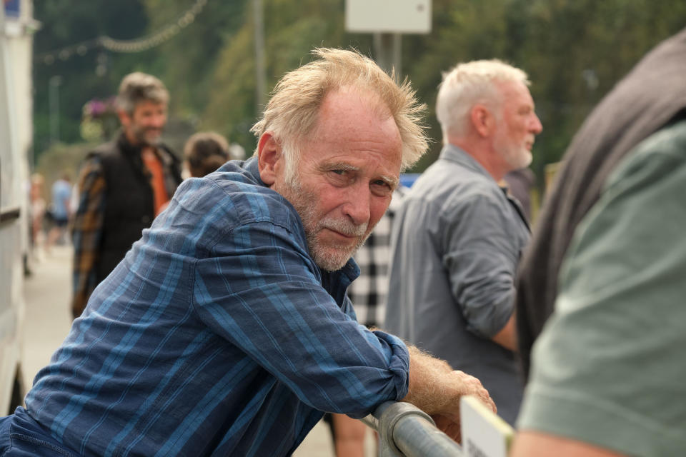 Jaime (Danny Webb) leans on a railing at the harbour, with his head turned to the side and looking into the camera