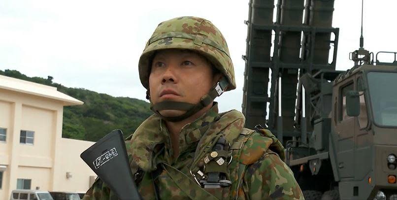 A member of the Japan Self Defense Forces stands in front of a mobile missile launcher at a newly-built base on the tiny, far-southern Japanese island of Ishigaki, which is closer to Taiwan than Japan's main island. / Credit: CBS News/Randy Schmidt  