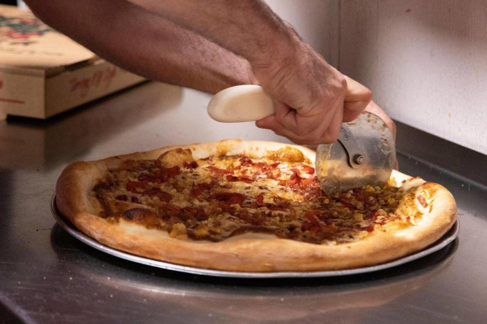 A pizza being cut at Village Idiot Pizza.